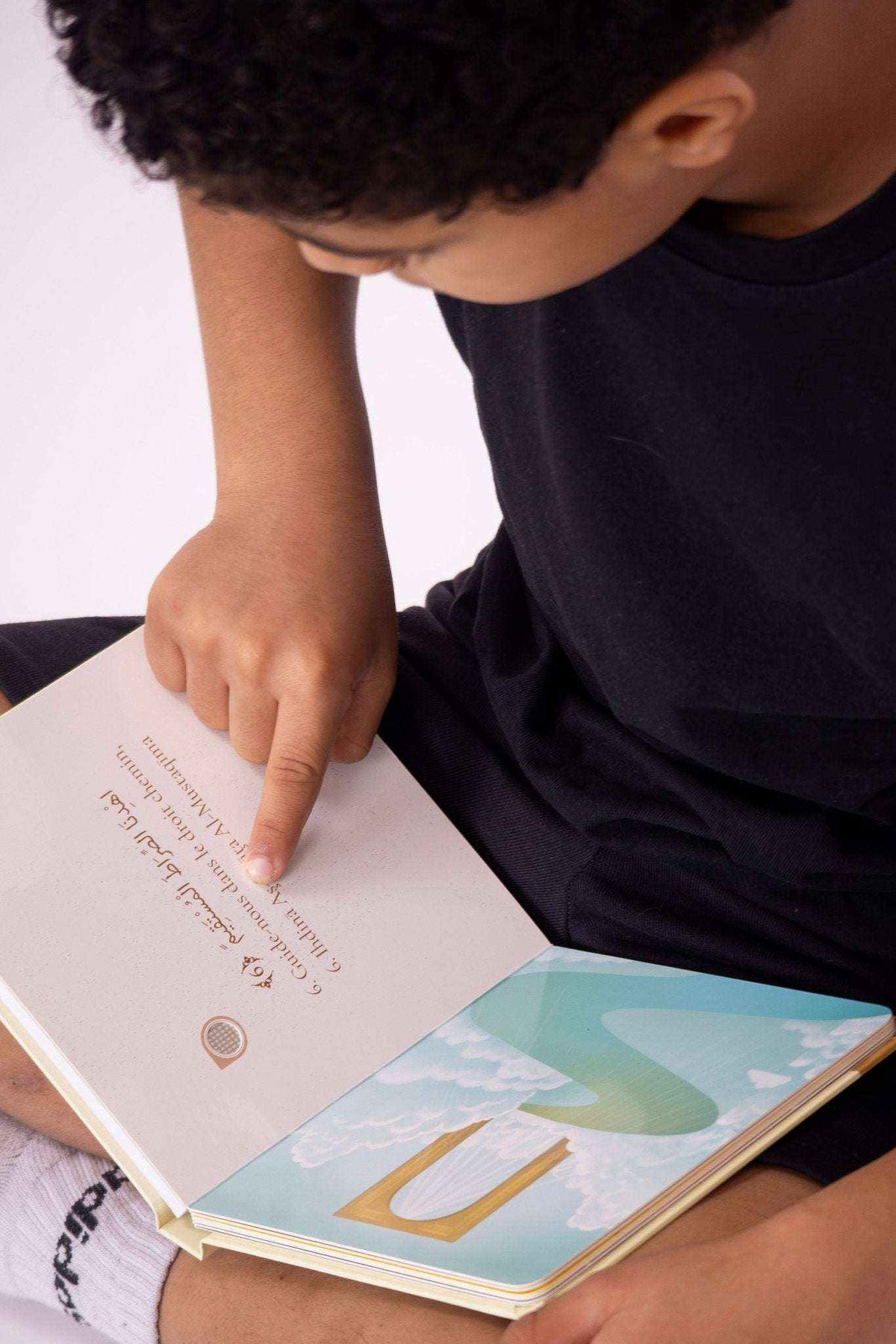 Kind liest im Hörbuch mit Suren auf Arabisch und Deutsch